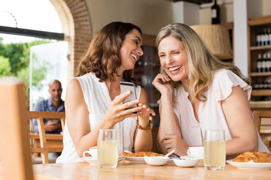 dos mujeres rien en un café