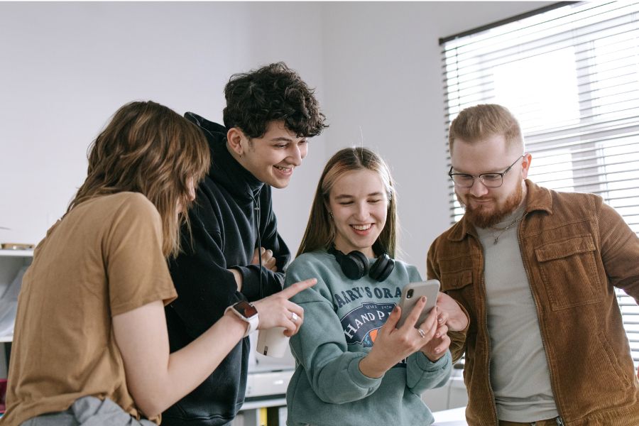 grupo de jóvenes mirando un movil riendo
